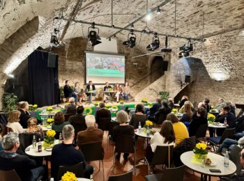 Blick in den Gewölbekeller mit Gästen an Tischen und dem Podium im Hintergrund