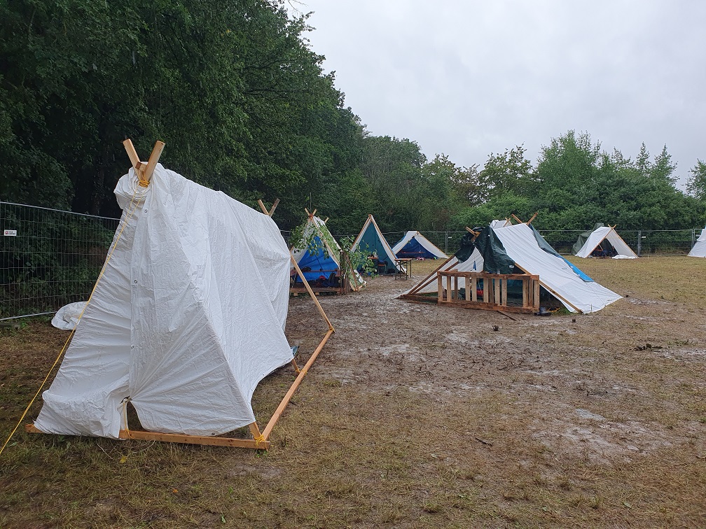 Wikingerzelte auf matschigem Untergrund mit Regenwetter im Hintergrund. 