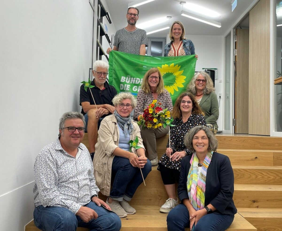 Bild auf einer Treppe. Mit Banner der Grünen in den Händen und einer Sonnenblume sitzt der neu gewählte Vorstand und Kerstin Celina, Gerhard, Müller, Christina Feiler, Sven Winzenhörlein und Jessica Hecht