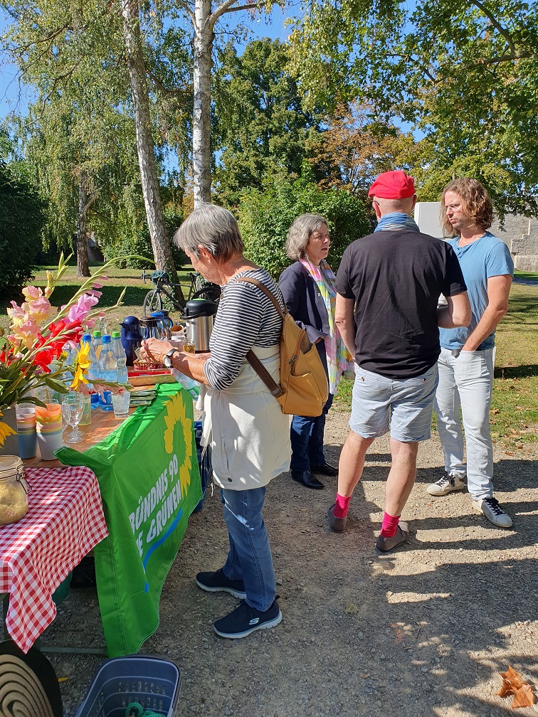 Foto von Bürger*innen, die sich mit MdL Kerstin Celina unterhalten. An der Seite ist der aufgebaute Brunch zu sehen.