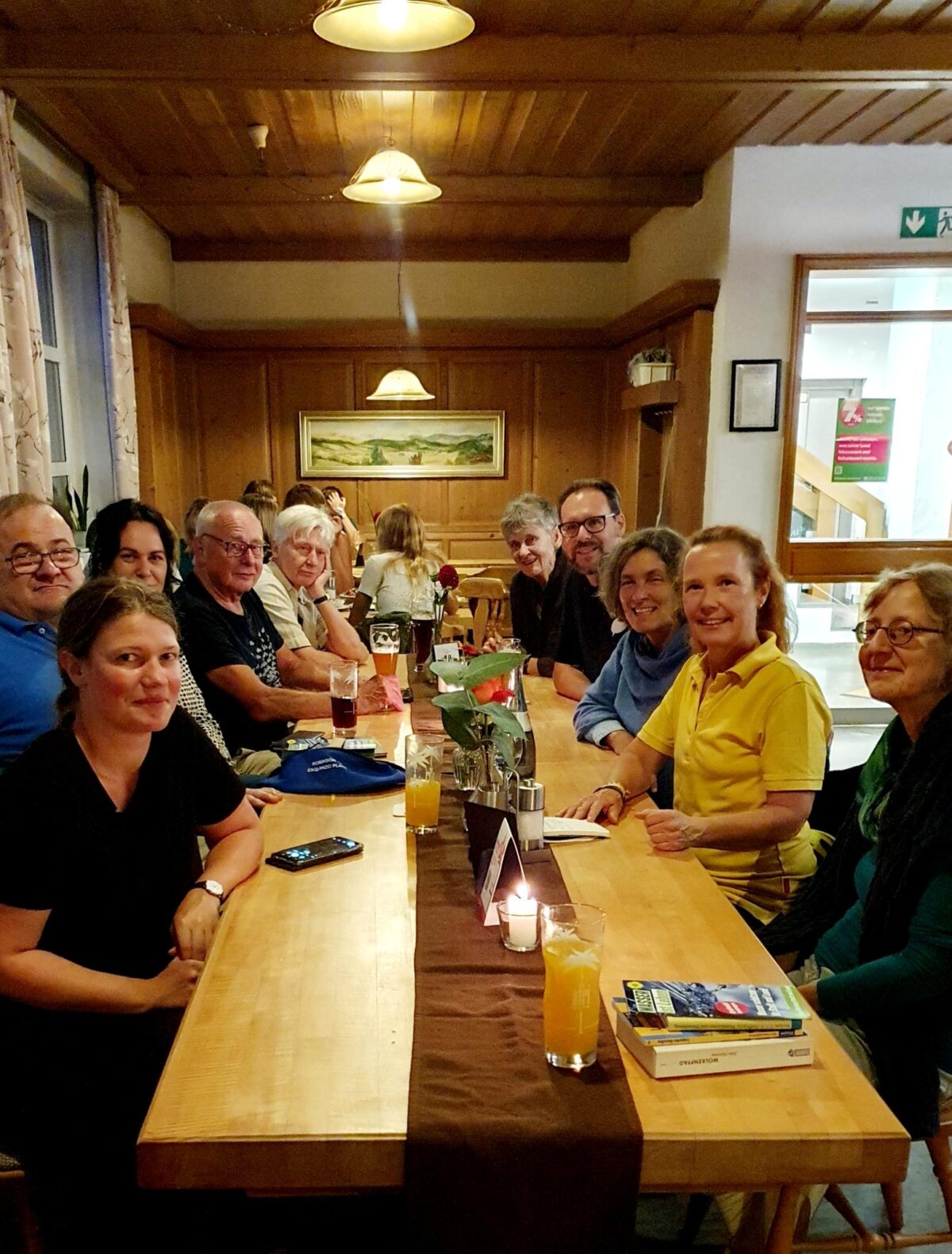 Gruppenfoto in einer Gastwirtschaft, mit einer Gruppe an Männern und Frauen