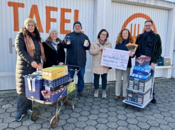 Vor den Garagen der Tafel stehen sechs Personen mit Körben und "Spendenplakat" in der Hand