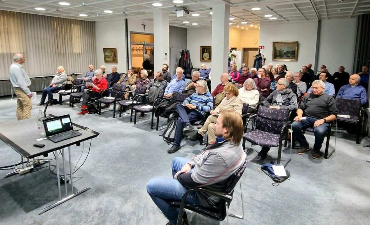 Das Publikum aus ca. 60 Personen - vor allem Menschen zwischen schätzungsweise 50 und 70 Jahren - hören aufmerksam Günter Thein zu, der die Veranstaltung hier einleitet.