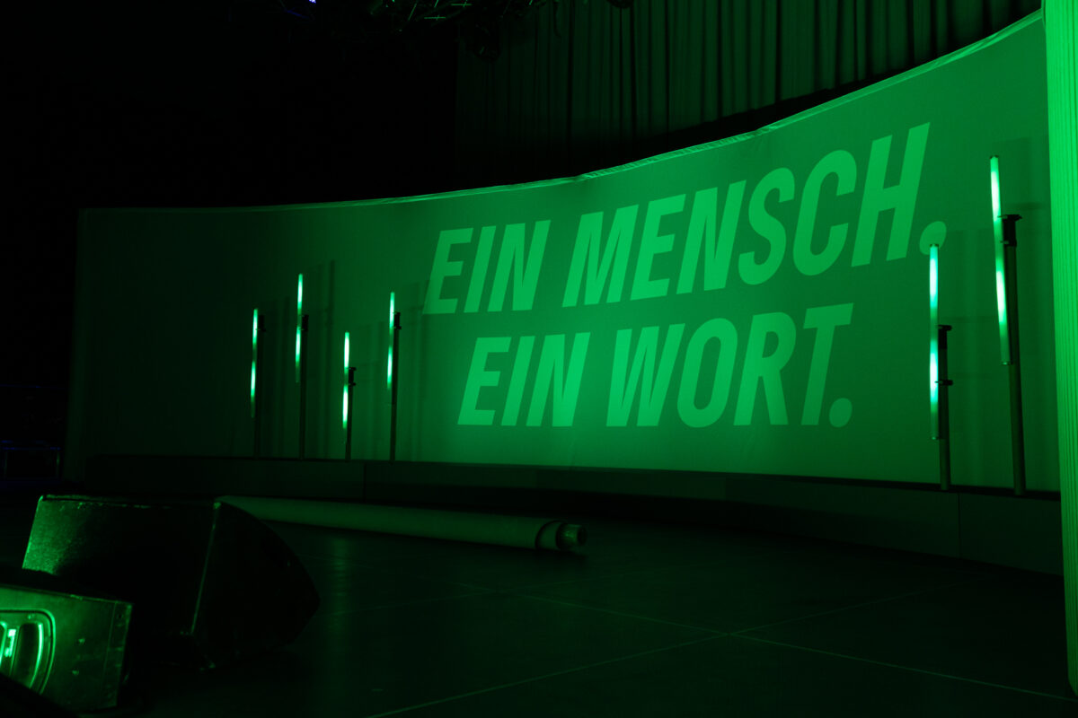 Wahlkampfslogan der Grünen "Ein Mensch ein Wort" auf der Bühne in Grün